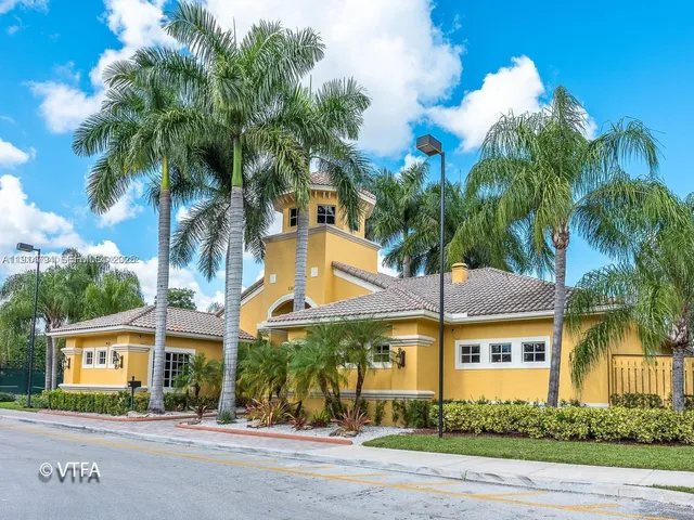 a view of a white house with a tree in front of it