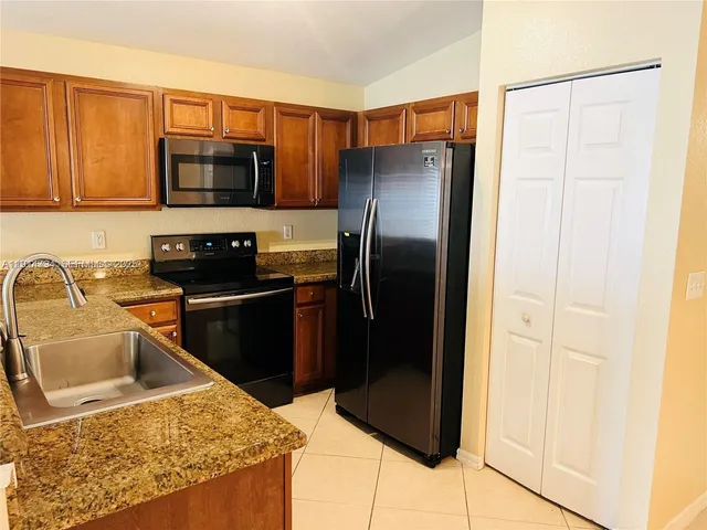 a kitchen with stainless steel appliances granite countertop a refrigerator a stove and a sink with wooden floor