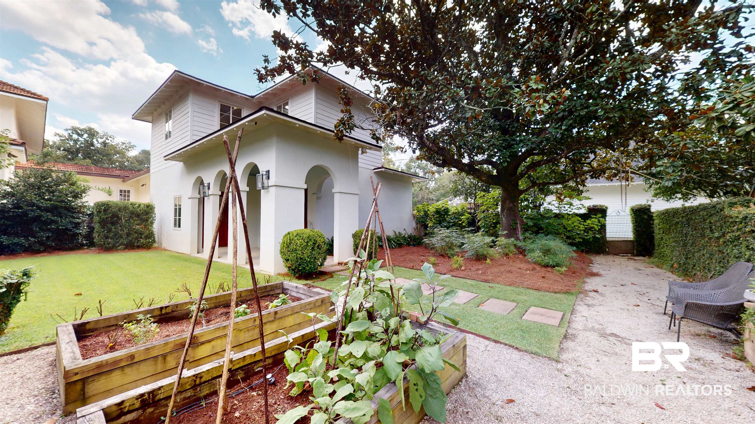 211 Lanier Avenue Mobile, AL 36607 - Photo 61 of 73 Rear view of house with a vegetable garden, a lawn, and stucco siding