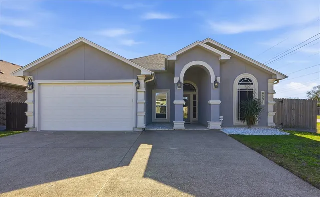 a view of a house with a yard and large tree