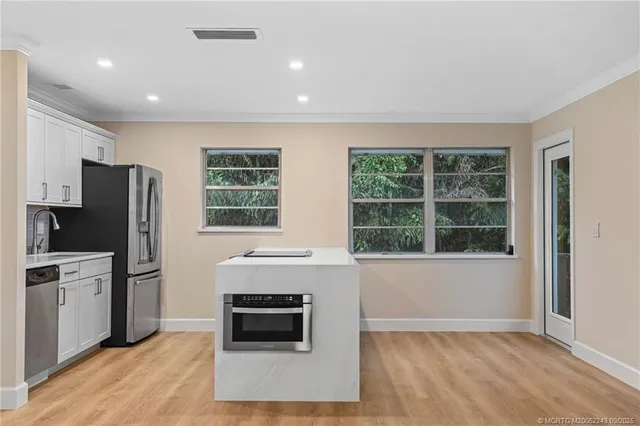 a living room with stainless steel appliances furniture a fireplace and a window