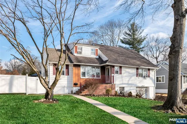 a view of a yard in front of a house with plants and large tree