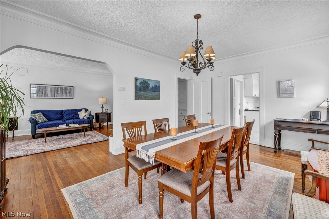 2410 Overlook Road Cleveland Heights, OH 44106 - Photo 13 of 50 Dining room featuring arched walkways, hardwood / wood-style floors, a textured ceiling, ornamental molding, and hanging lights