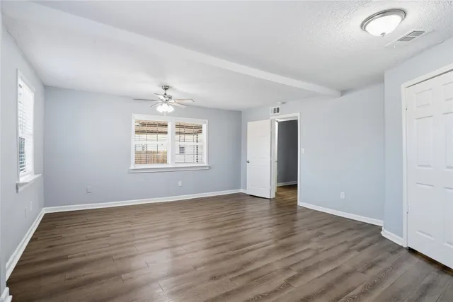 an empty room with wooden floor cabinet and windows