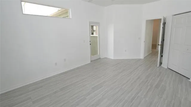 a view of an empty room with wooden floor and a window