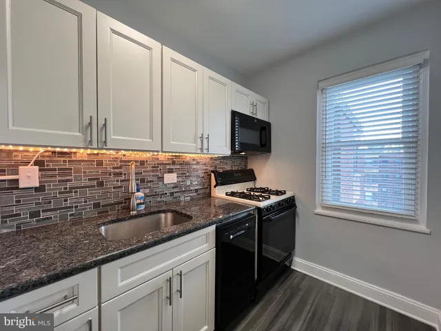 a kitchen with granite countertop a sink a stove and wooden cabinets