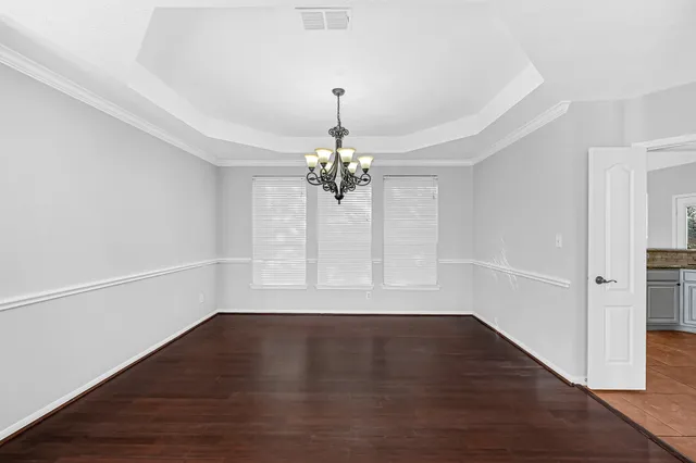 a view of a room with wooden floor chandelier and a window