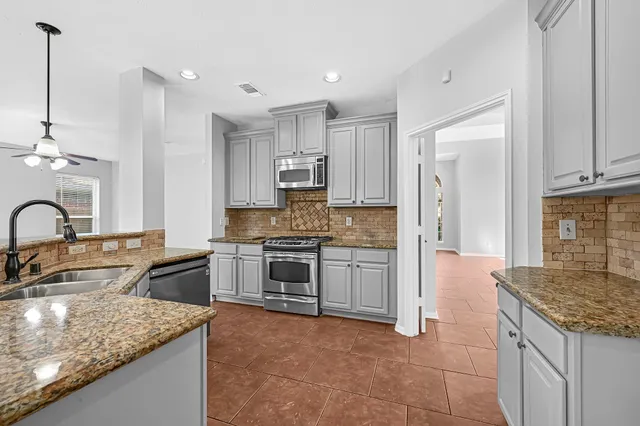 a kitchen with kitchen island granite countertop a stove sink and refrigerator