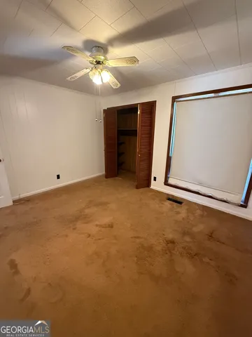 an empty room with closet and a ceiling fan