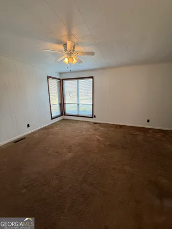 an empty room with a ceiling fan and window