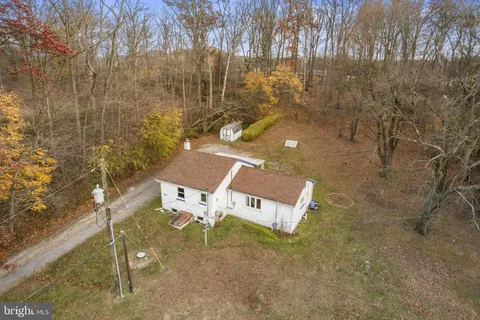 an aerial view of a house with swimming pool and large trees