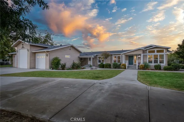 a view of a white house next to a yard with big trees