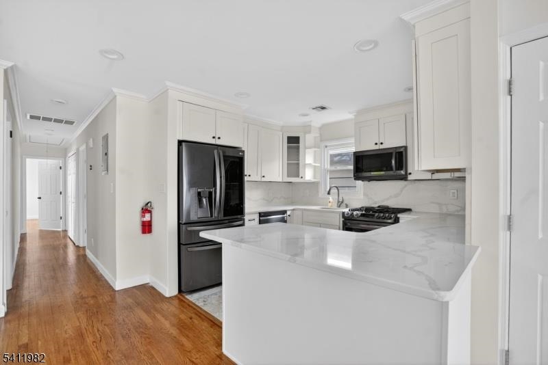 16 George Street, Unit 2 Bayonne, NJ 07002 - Photo 2 of 10 a kitchen with a refrigerator a stove top oven a sink a dining table and chairs