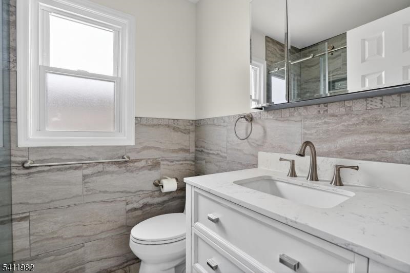 16 George Street, Unit 2 Bayonne, NJ 07002 - Photo 7 of 10 a bathroom with a granite countertop toilet sink and mirror