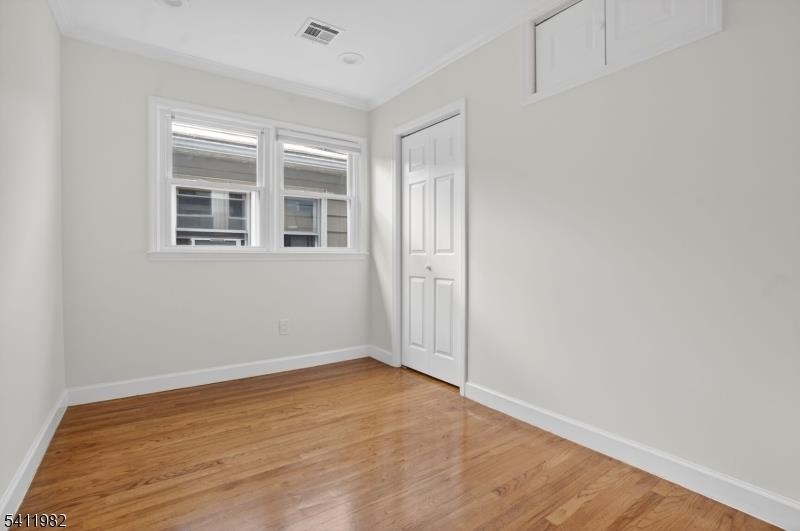 16 George Street, Unit 2 Bayonne, NJ 07002 - Photo 8 of 10 a view of an empty room with wooden floor and a window