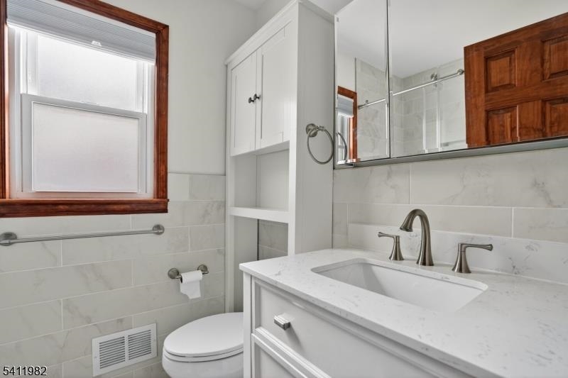 16 George Street, Unit 2 Bayonne, NJ 07002 - Photo 10 of 10 a bathroom with a sink a toilet and a mirror