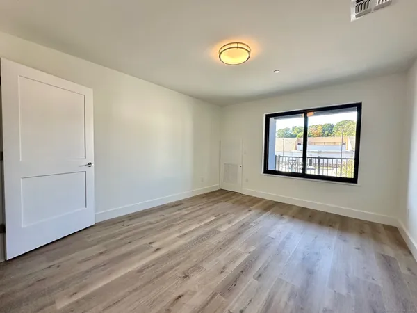 an empty room with wooden floor and windows
