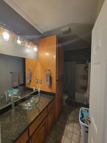 a bathroom with a granite countertop sink a toilet and a mirror