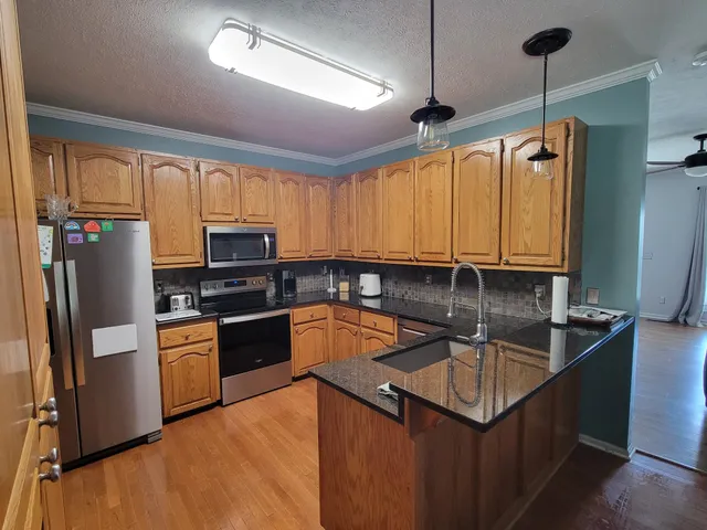 a kitchen with stainless steel appliances granite countertop a sink a stove and refrigerator