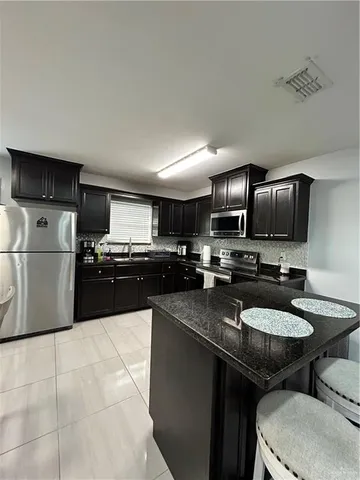 a kitchen with stainless steel appliances granite countertop a sink a stove top oven a counter space and cabinets