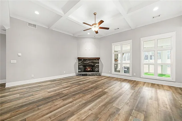 an empty room with wooden floor fireplace and windows