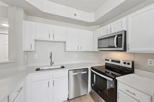 a kitchen with cabinets stainless steel appliances and a sink