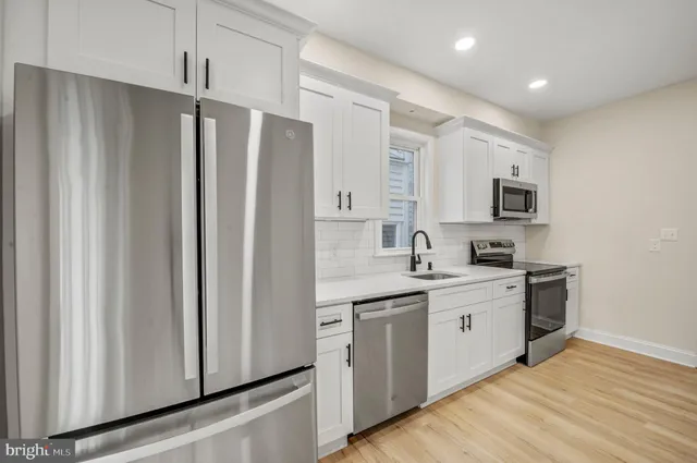 a kitchen with stainless steel appliances granite countertop a refrigerator sink and white cabinets