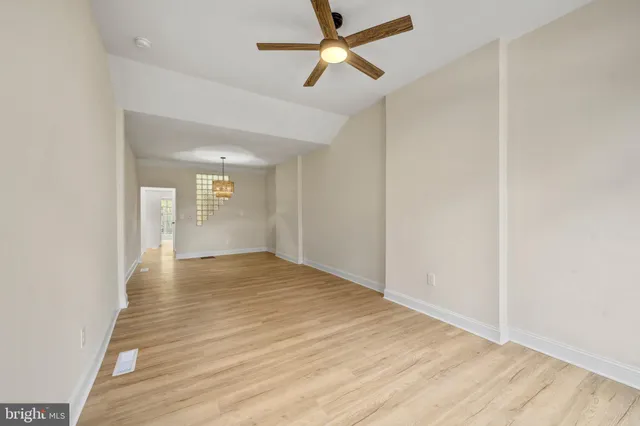 a view of empty room with wooden floor and fan