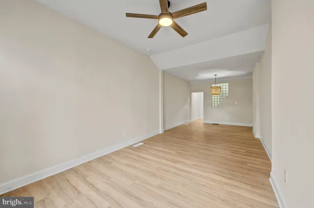 a view of empty room with wooden floor and fan
