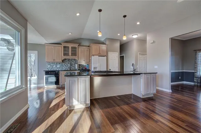 a kitchen with granite countertop a stove top oven a sink a counter space and cabinets