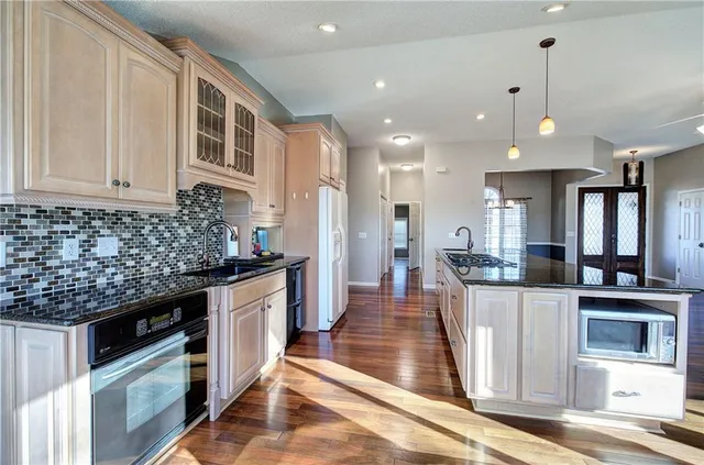 an empty room with wooden floor chandelier fan and windows
