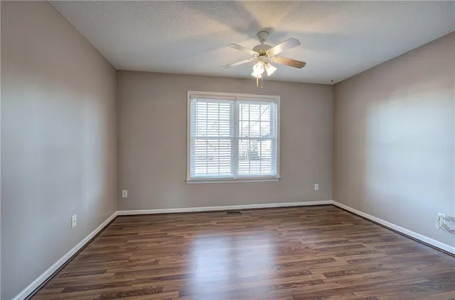 a view of an empty room with window and wooden floor