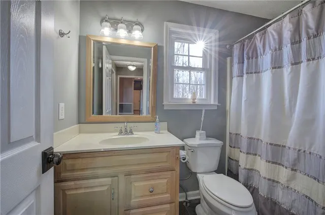 a view of an empty room with wooden floor and a ceiling fan