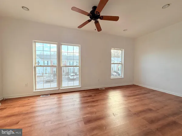 a view of empty room with wooden floor and fan