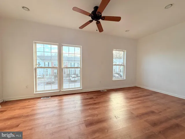 a view of empty room with wooden floor and fan