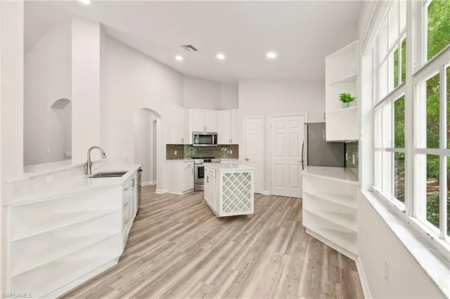 a large kitchen with kitchen island white cabinets and stainless steel appliances