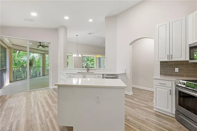 a kitchen with kitchen island a sink appliances cabinets and a large window
