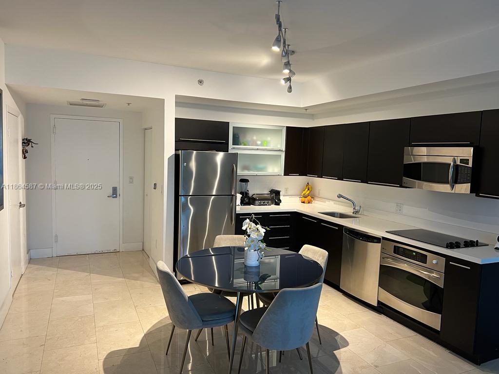 90 Southwest 3rd Street, Unit 2103 Miami, FL 33130 - Photo 6 of 31 a kitchen with stainless steel appliances a stove a refrigerator and a dining table