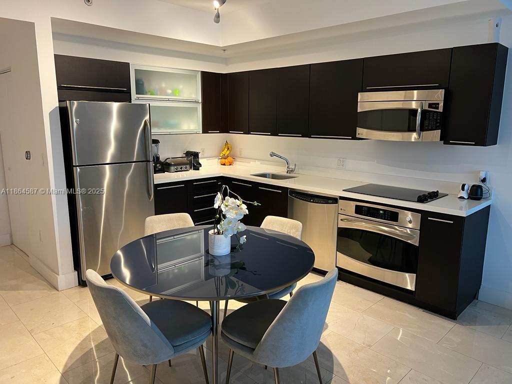 90 Southwest 3rd Street, Unit 2103 Miami, FL 33130 - Photo 7 of 31 a kitchen with stainless steel appliances a dining table and chairs