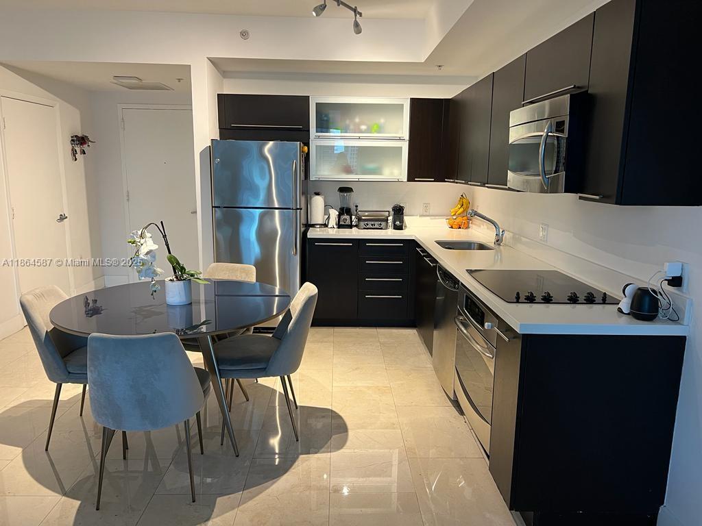 90 Southwest 3rd Street, Unit 2103 Miami, FL 33130 - Photo 8 of 31 a kitchen with stainless steel appliances granite countertop a stove refrigerator a microwave oven with a dining table and chairs