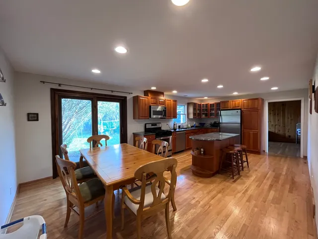 a kitchen with a dining table chairs and wooden floor