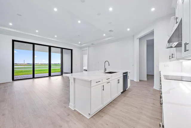 a large kitchen with stainless steel appliances a large counter top a stove and a refrigerator