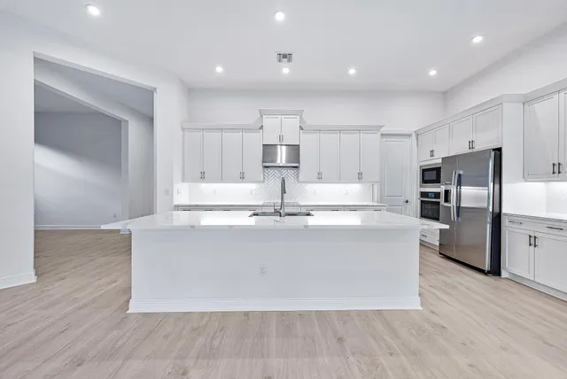 a large kitchen with stainless steel appliances a large counter top a stove and a refrigerator