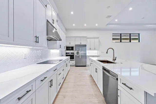 a large kitchen with stainless steel appliances granite countertop a sink and cabinets