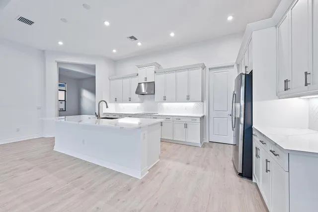 a large kitchen with cabinets wooden floor and stainless steel appliances