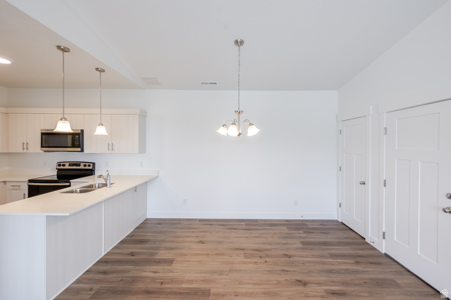 675 West 4500th South, Unit P301 Mapleton, UT 84664 - Photo 13 of 16 Bright kitchen and dining area featuring light wood-finish cabinetry, a black range with a microwave, stainless steel sink, recessed lighting, and wood-finish flooring