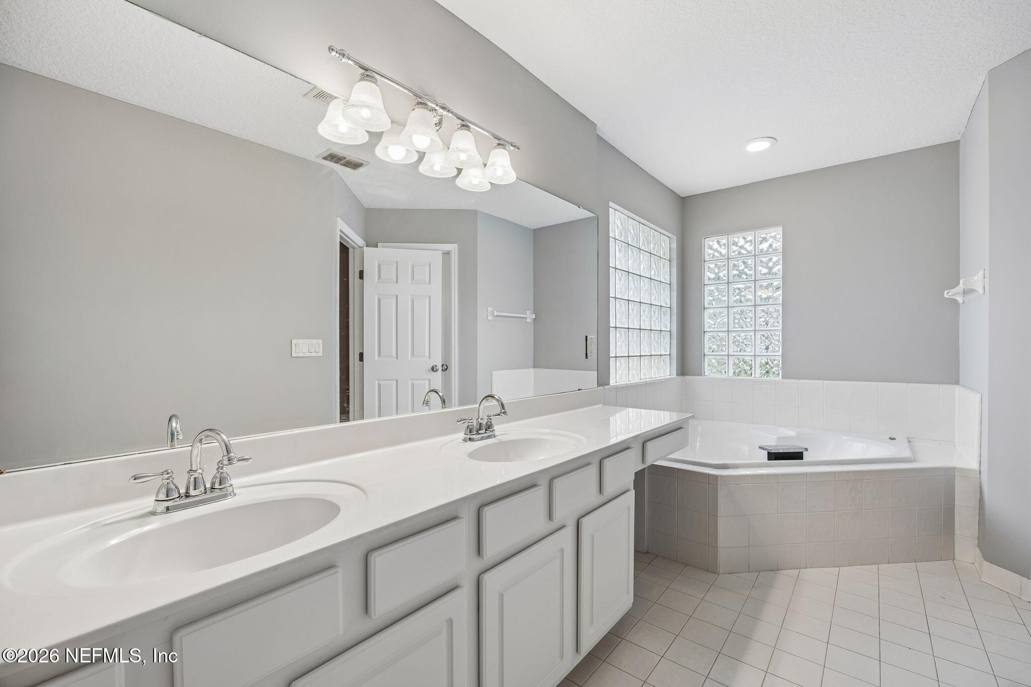 213 Springwood Lane St. Johns, FL 32259 - Photo 33 of 78 a bathroom with a double vanity sink a large mirror and bathtub