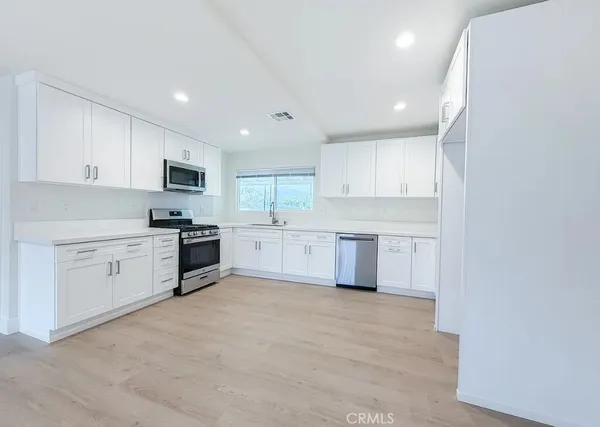 a kitchen with white cabinets stainless steel appliances and sink