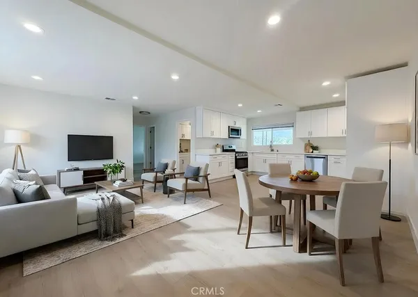 a living room with furniture kitchen view and a flat screen tv