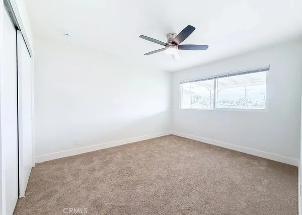 an empty room with windows and fan